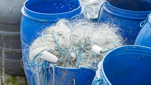 White fishing nets inside blue plastic barrels