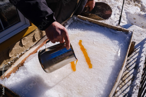 Pouring hot maple syrup on snow to make maple taffy
