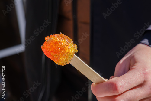 Hand holding a fresh maple taffy stick in winter
