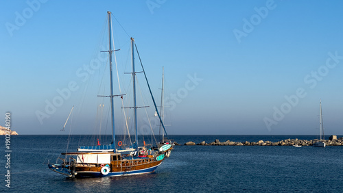 Traditional wooden gulet sailboat anchored in the calm deep blue waters of the Aegean Sea at Knidos harbor, Turkey
