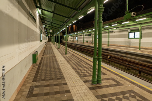 Empty Vienna metro platform at night with green columns and canopy. Vienna, Austria