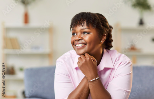 Obraz na plátne Portrait of a happy african american woman smiling warmly, sitting on sofa at home