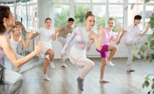 Tableau sur toile Girl teen performs modern dances repeats movements of unrecognizable teacher together with friends during lesson at choreographic school