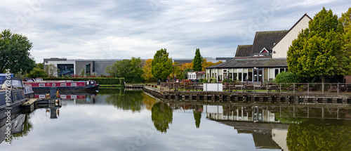 Obraz na plátně Tranquil Canalside Village Scene With Boats, Cafes, And Reflections On Still Wat