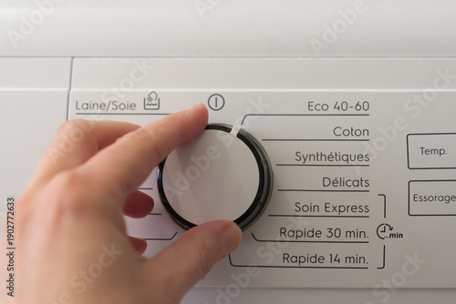 Female hand choosing eco programme on washing machine