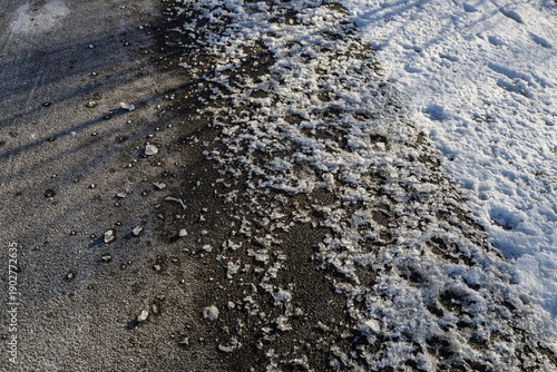 Fotografija Melting snow and ice on asphalt in harsh sunlight.