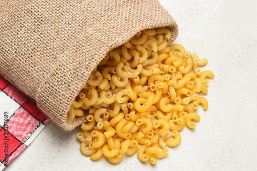 Foto High angle shot of Macaroni Noodles spilling out of a burlap bag onto a light gray table