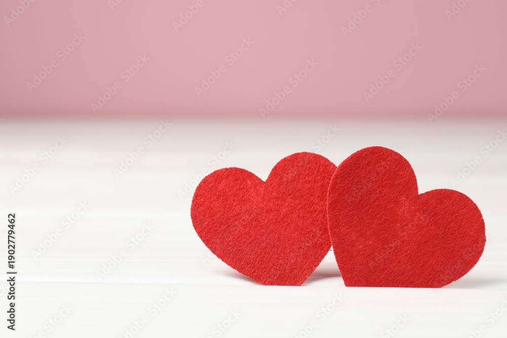 Obraz premium Love. Red decorative hearts on white table against pink background, closeup. Space for text