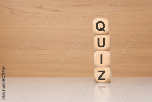 Vertical stack of wooden cubes spelling QUIZ on office desk