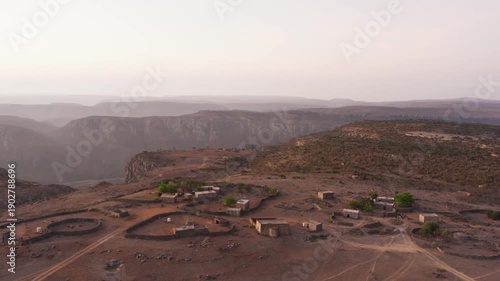 Aerial view of a remote village nestled in the mountains of Socotra, Yemen, showcasing traditional architecture and a majestic mountainous backdrop