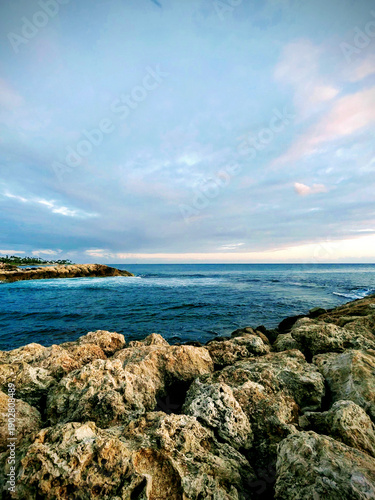 Sunset over the tranquil waters of Ko Olina, Oahu, revealing rocky formations and a serene coastline