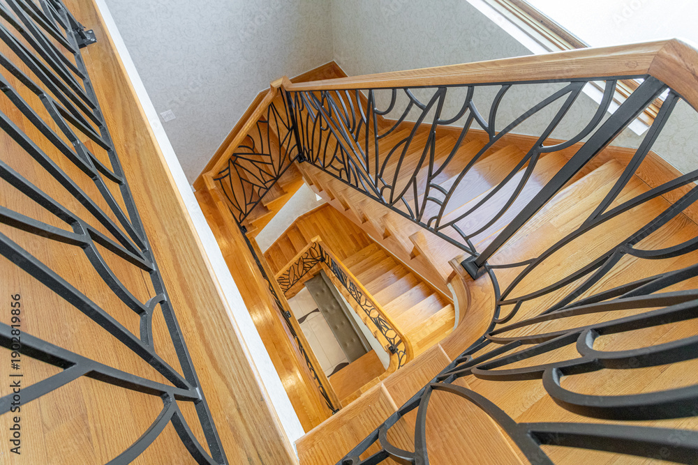 Obraz premium Wooden staircase with decorative metal railing viewed from above