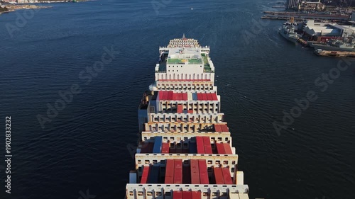 Large Cargo Ship Loaded With Multicolored Containers Traverses Canadian Waters. Aerial view Illustrates Modern Global Freight And Port-To-Port Logistics. Canada, Nova Scotia, Halifax. 