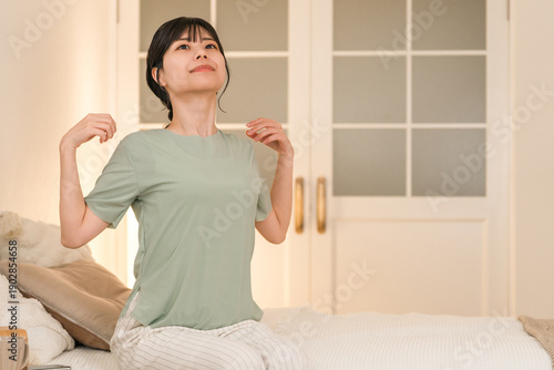 Fotografi Young Asian woman suffering from stiff shoulders in her bedroom at night