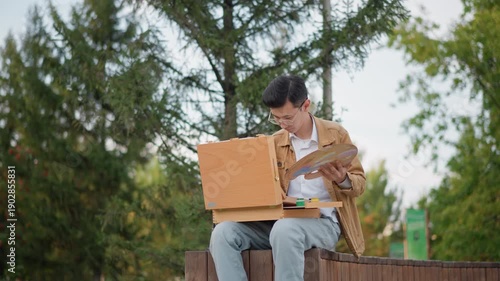 park easel illustrator studying color palette young creator reviewing reference and mixing paints on wooden palette, seated on bench under tall trees, careful brush strokes and compositional study,