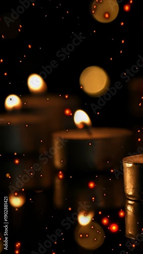 Vertical video: Three tealights glowing, embers bursting and sweeping over bokeh, adding motion