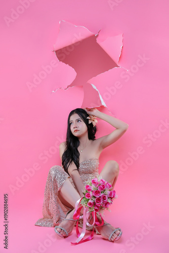 Creative Valentine portrait of beautiful Asian woman with pink roses through torn pape