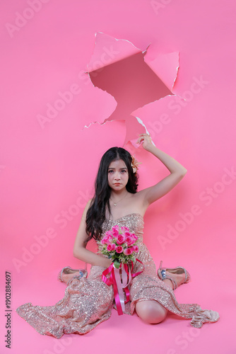 Creative Valentine portrait of beautiful Asian woman with pink roses through torn pape