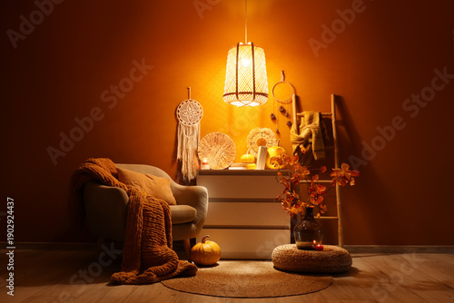 Fotografie Comfortable armchair, chest of drawers, stepladder and autumn decor in interior