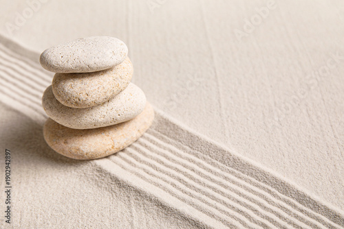 Photography Composition with stack of spa stones and lines on sand as background, closeup