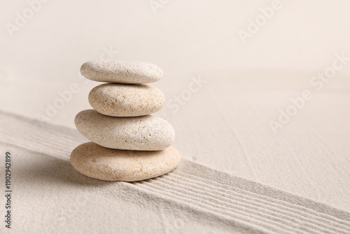Photography Composition with stack of spa stones and lines on sand as background, closeup
