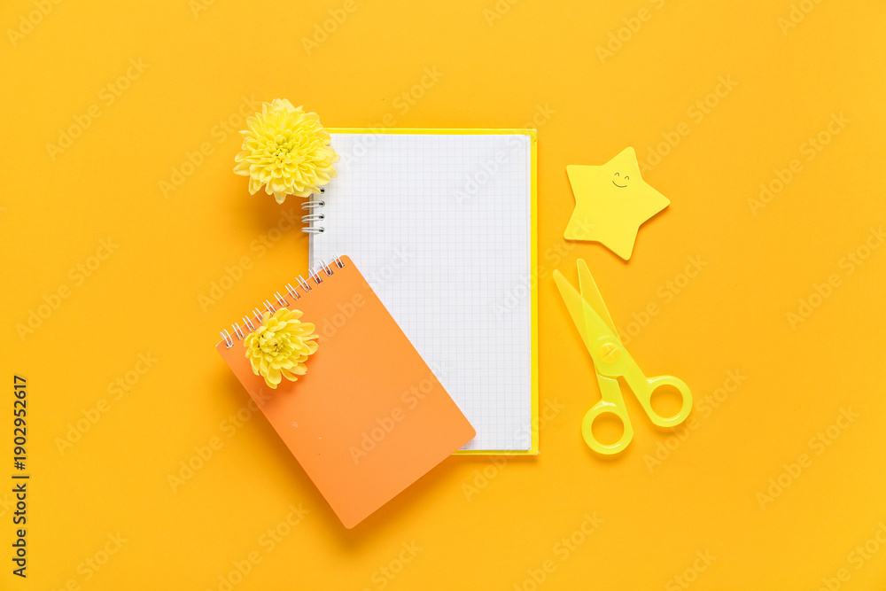 Fototapeta premium Notebooks, sticky notes and flowers on orange background