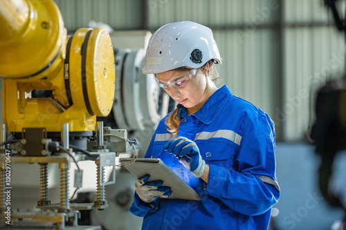 woman engineer in uniform helmet inspection check control heavy machine robot arm construction installation in industrial factory. technician worker check for repair maintenance electronic operation