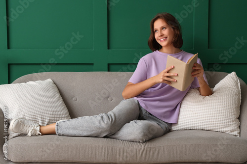 Dreamy young woman reading ...