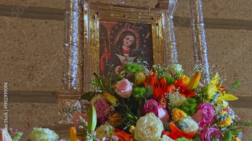 Close-up of venerated painting of Nuestra Señora de la Altagracia surrounded by vibrant floral arrangement at Higüey Basilica, Dominican Republic