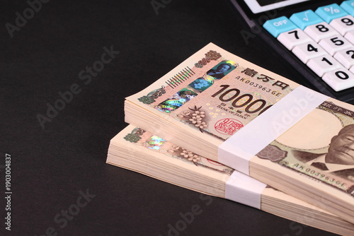 2つの札束と電卓（家計・ビジネス・資産運用イメージ）