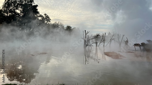 Obraz na płótnie A horizontal photograph of a natural landscape, depicting the surface of a hot thermal spring or mineral pool, shrouded in dense steam
