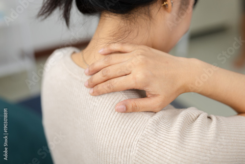 Close up of women touching neck and shoulder with pain at home. Muscle tension, neck strain, stress, fatigue, office syndrome, unhealthy posture, daily lifestyle discomfort concept.