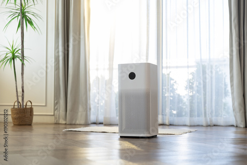 Air purifier in bright living room by large window, filtering dust and allergens for clean indoor air, healthy home environment, minimal interior design today.