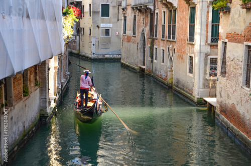 Italy, Venice, September 29, 2025,  A gondolier in a red and white striped shirt is transporting tourists in Venice