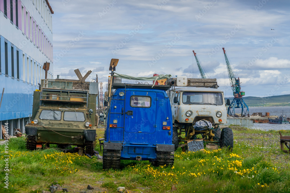 Fototapeta premium UAZ and 4WD vehicles including cargo trucks, snowmud rover and rugged ATV essential for Chukotka rugged tundra near Tavayvaam port, Arctic Russia.