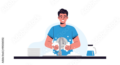 Smiling young man in a blue t-shirt washes dishes with soapy water at a kitchen sink with clean plates on the side.