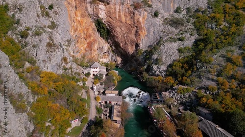 Epic aerial view of the historic Blagaj Tekke dervish monastery under a massive cliff, crystal clear source of the Buna river, Bosnia and Herzegovina, 4K