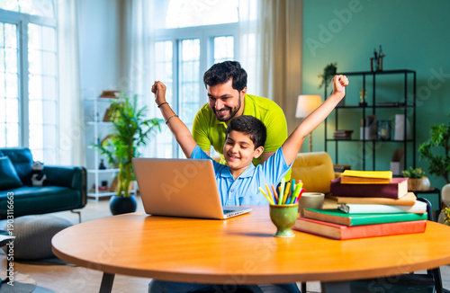 Indian asian kid studying on laptop at home while father guides him patiently