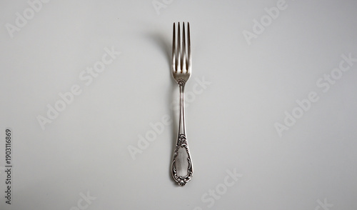 Εκτύπωση καμβά Elegant silver or silver plated dining fork with an ornate handle, isolated on a solid gray background