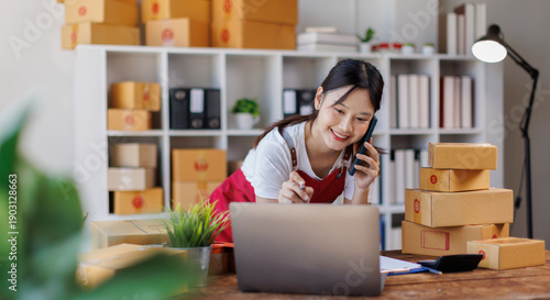 Tableau sur toile Asian woman small businesses SME owners asian female entrepreneurs call phone on receipt box and check online orders to prepare to pack the boxes, sell to customers, SME business ideas online