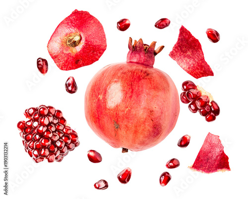dynamic composition of ripe pomegranates and scattered seeds floating on white.