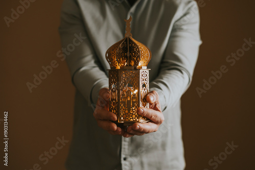 Ornamental Arabic lantern glowing in hand. Festive greeting card for Muslim holy month Ramadan Kareem