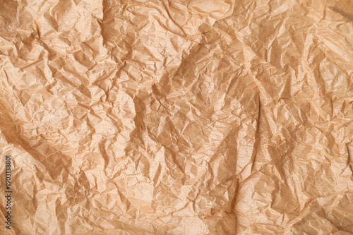 Closeup of wrinkled crumpled brown paper texture. Macro photography of paper folds, parchment. Abstract background. Baking paper. Mockup for lettering, words, or text
