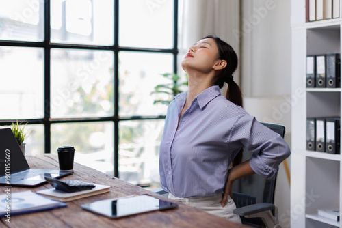 Fotografie Body muscles stiff problem, ache asian young woman pain neck and shoulder while sitting work on chair at home, male holding massaging rubbing, hurt or sore body