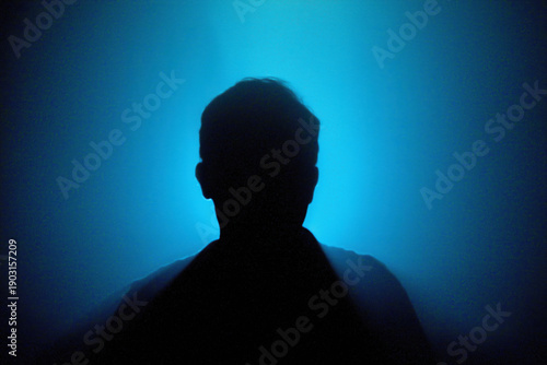 Mysterious Silhouette Against Blue Light Background in Dark Setting