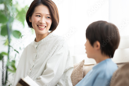 本を読む男の子とソファに座る母親