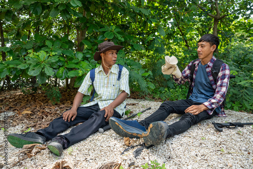 Two male friends with backpacks on vacation hiking through countryside together. Man tourists with backpacks and hiking equipment are walking in the forest. People on mountain hike with trekking poles