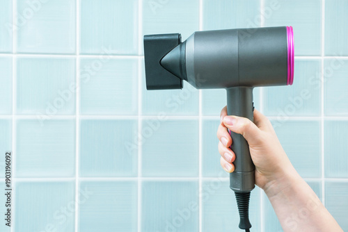 Foto Hand holding white hair dryer against blue tile background side view close-up