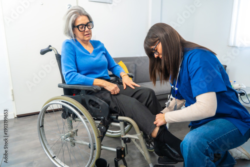 Fotografie Caretaker assisting senior woman in wheelchair getting dressed