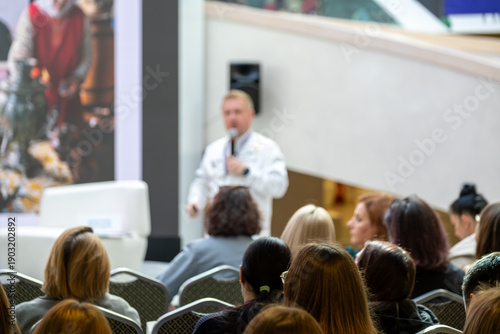 Wallpaper Mural Doctor in white coat delivers talk to seated audience in busy conference area Torontodigital.ca